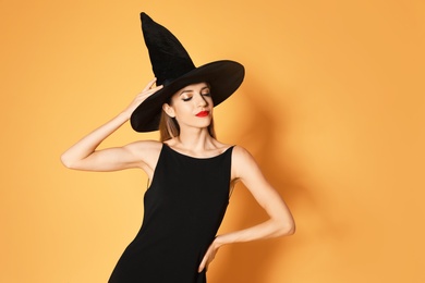 Beautiful woman wearing witch costume for Halloween party on yellow background, space for text