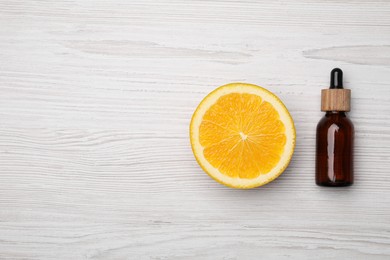 Photo of Bottle of citrus essential oil and fresh orange on white wooden table, flat lay. Space for text