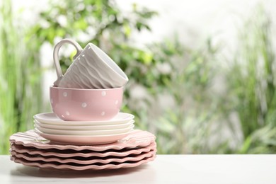 Beautiful ceramic dishware and cup on white table outdoors, space for text