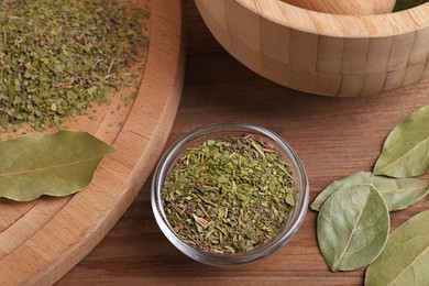 Photo of Whole and ground aromatic bay leaves on wooden table, above view