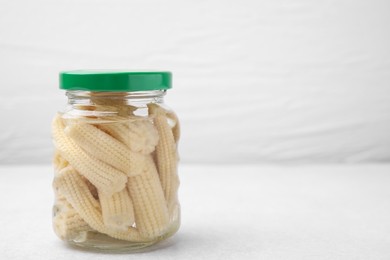 Canned baby corns on white table, closeup. Space for text