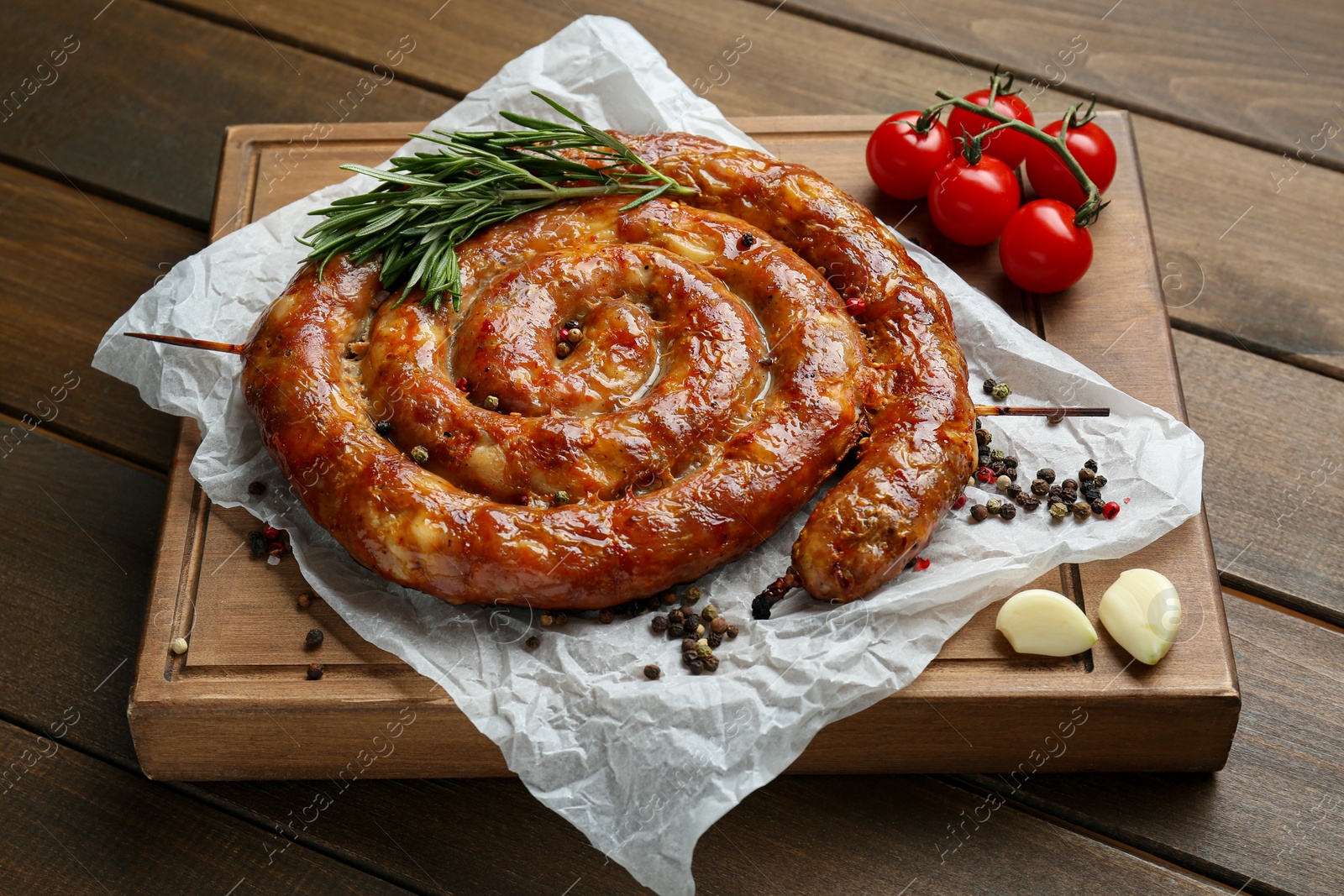 Photo of Delicious homemade sausages with spices and tomatoes on wooden table