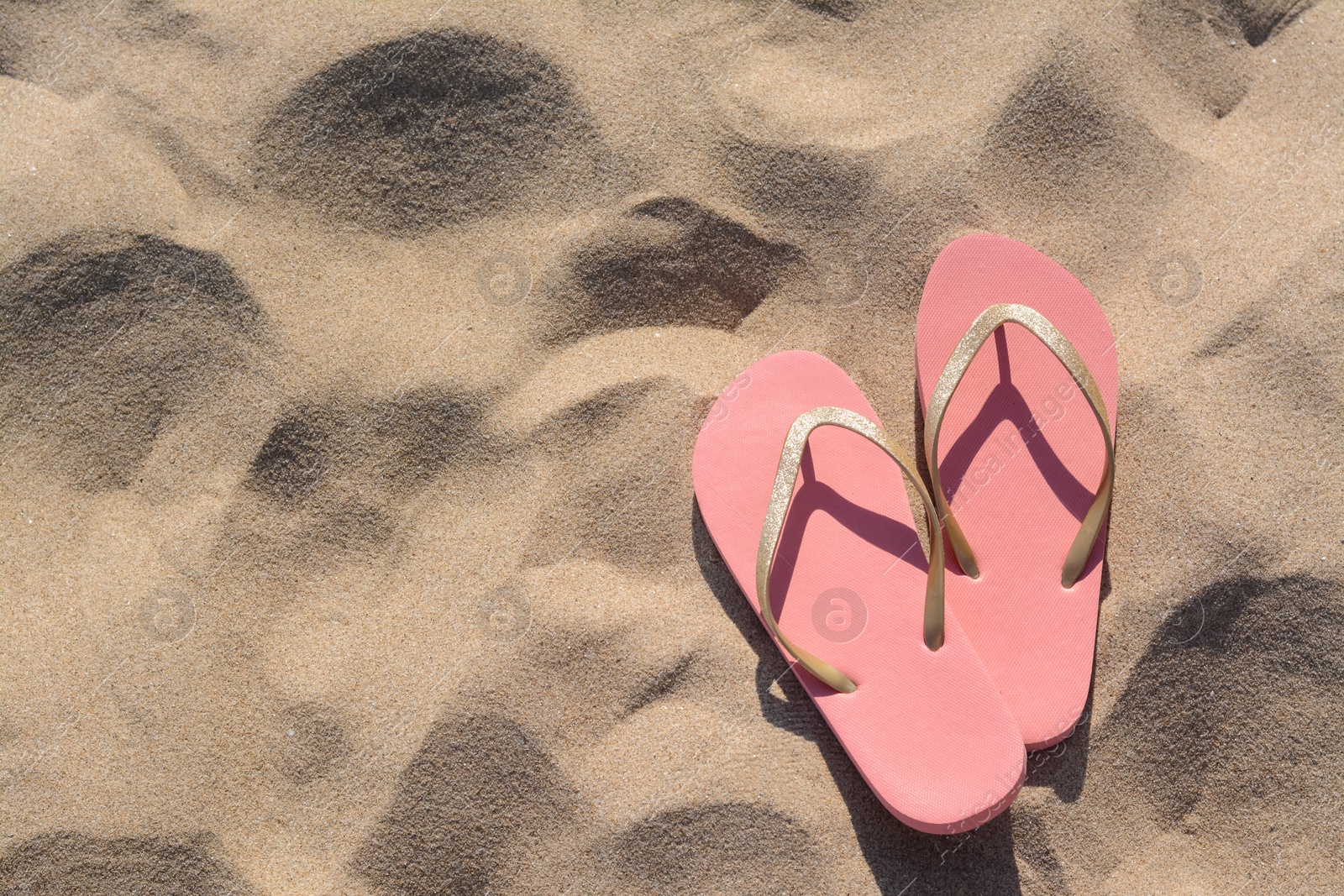 Photo of Stylish flip flops on sandy beach, flat lay. Space for text