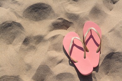 Stylish flip flops on sandy beach, flat lay. Space for text