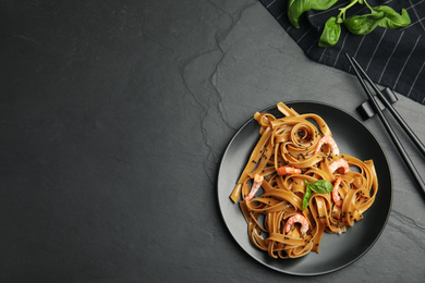 Tasty buckwheat noodles with shrimps served on black table, flat lay. Space for text