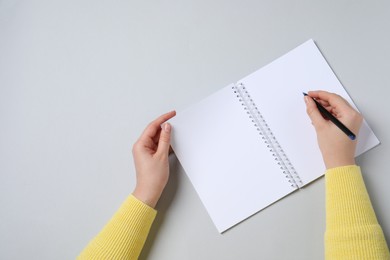 Woman with pen and notepad on light background, top view. Space for text