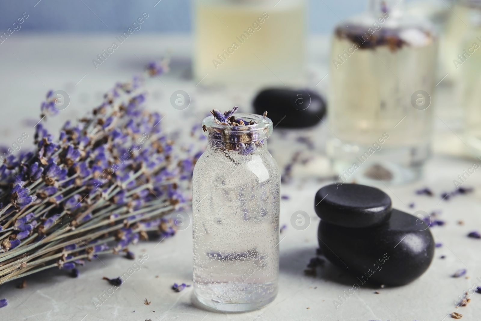 Photo of Bottles with natural herbal oil and lavender flowers on color table, closeup