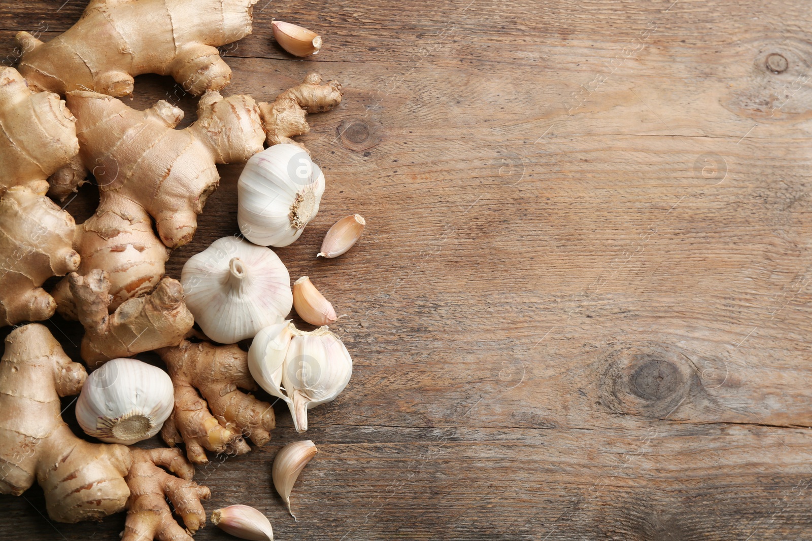 Photo of Ginger and fresh garlic on wooden table, flat lay with space for text. Natural cold remedies