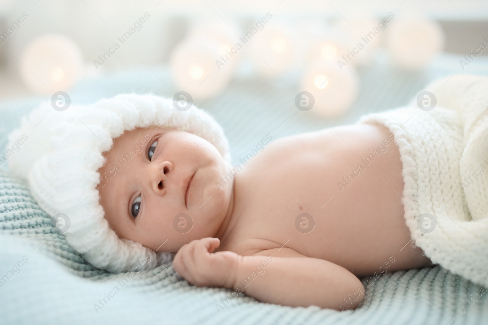 Photo of Adorable newborn baby in warm hat lying on bed