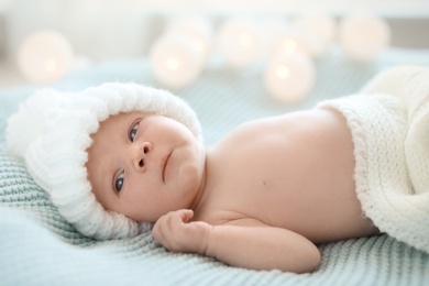 Photo of Adorable newborn baby in warm hat lying on bed