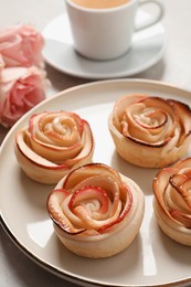 Photo of Freshly baked apple roses served on light table. Beautiful dessert