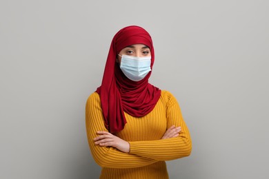 Photo of Portrait of Muslim woman in hijab and medical mask on light gray background