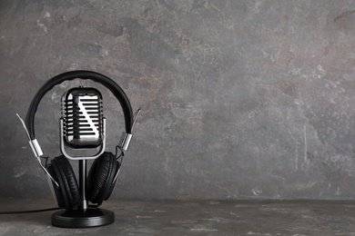 Photo of Retro microphone and headphones on table against grey background. Space for text