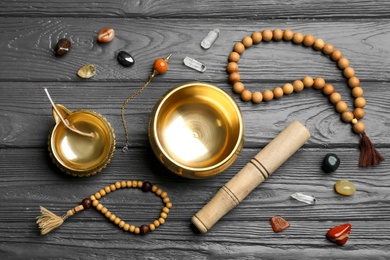 Photo of Flat lay composition with golden singing bowl on grey wooden table. Sound healing