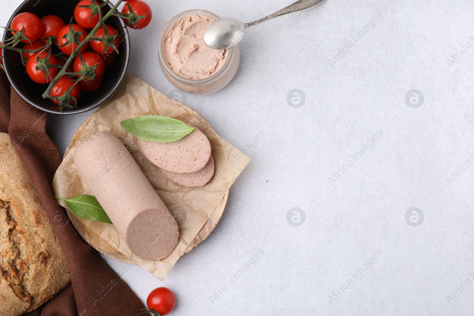 Photo of Delicious liver sausages, paste and cherry tomatoes on light grey table, flat lay. Space for text