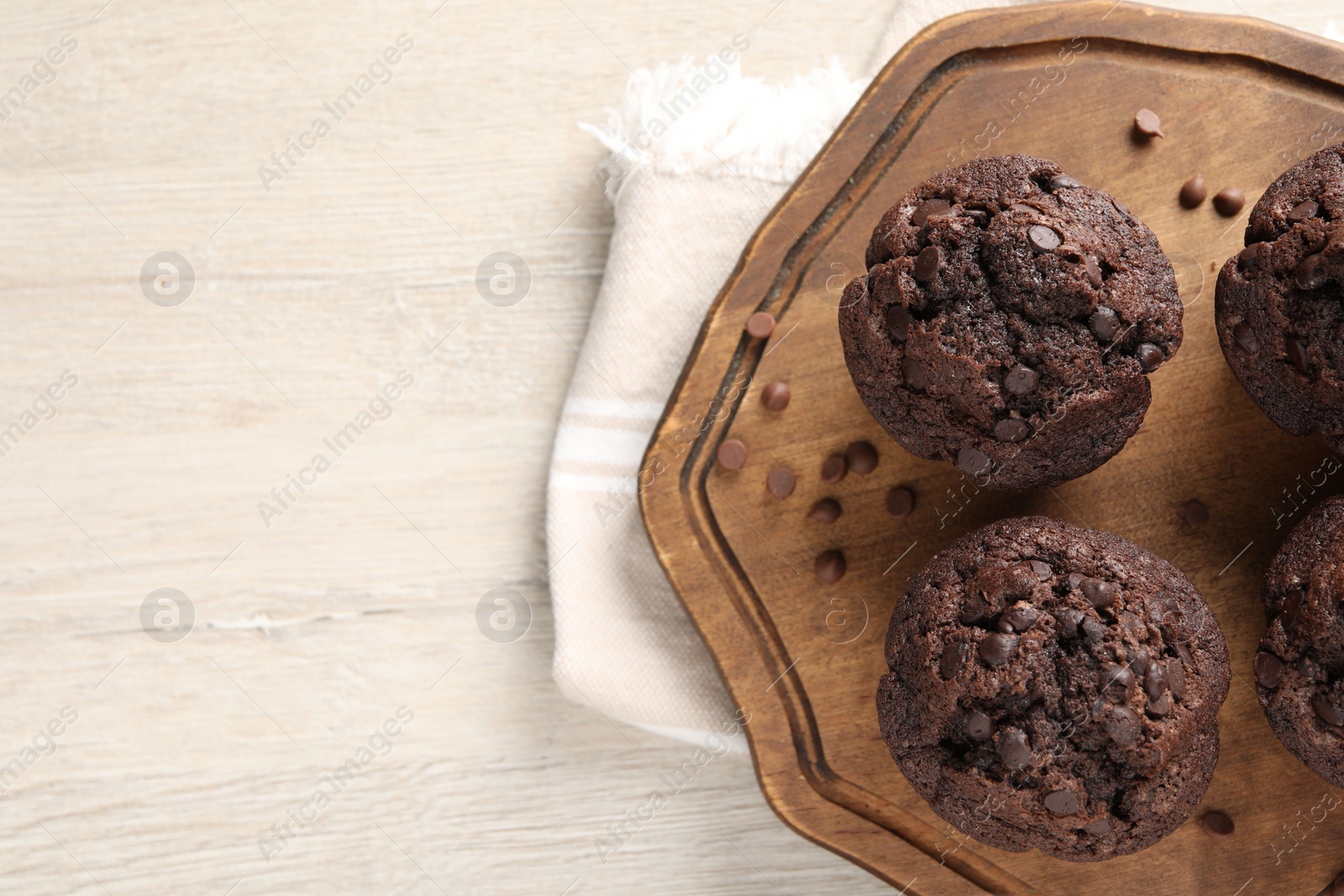 Photo of Delicious chocolate muffins on white wooden table, top view. Space for text