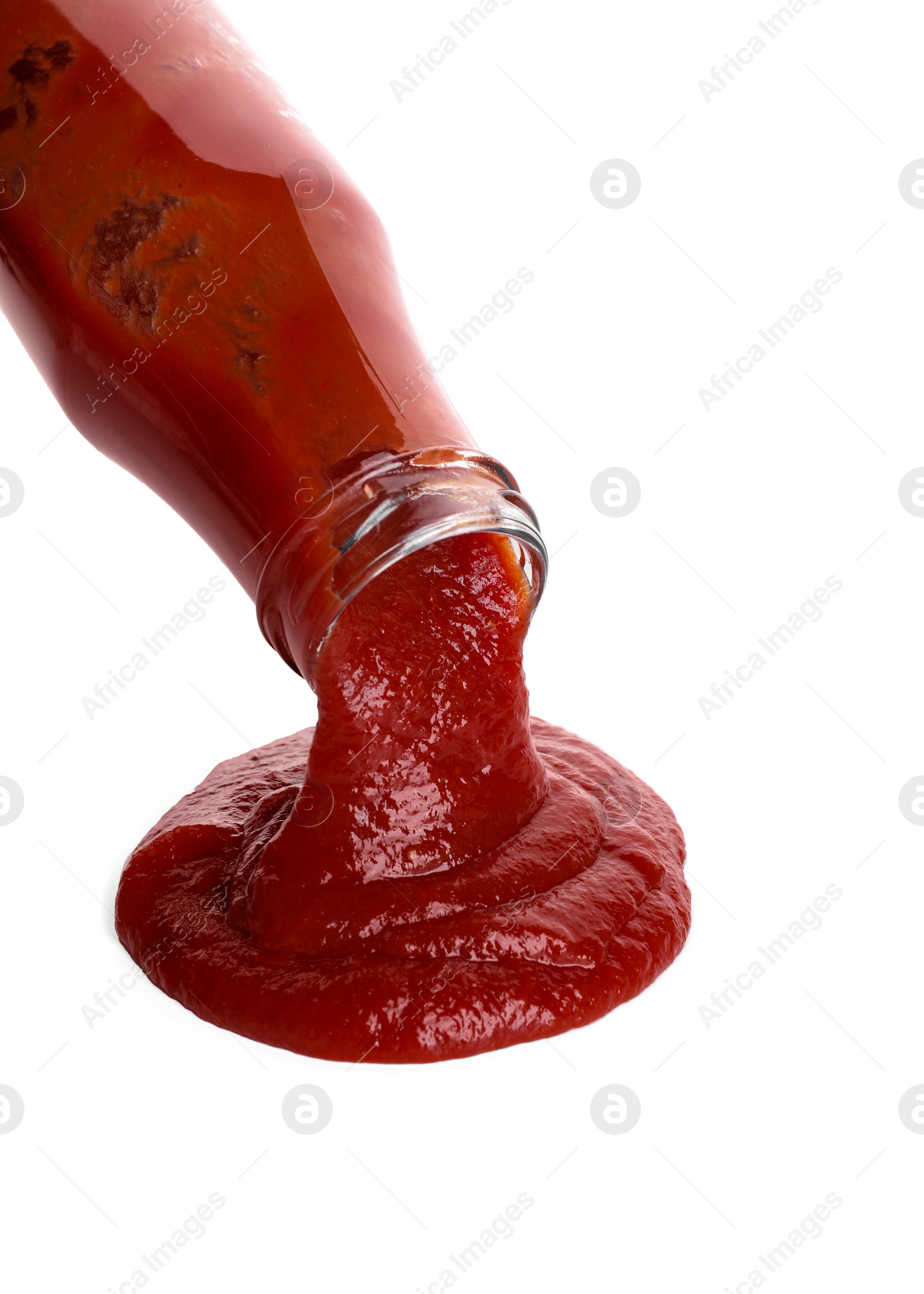 Photo of Pouring tasty ketchup from bottle isolated on white. Tomato sauce