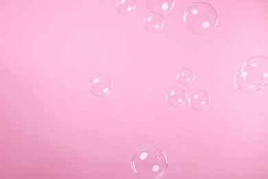 Photo of Many beautiful soap bubbles on pink background