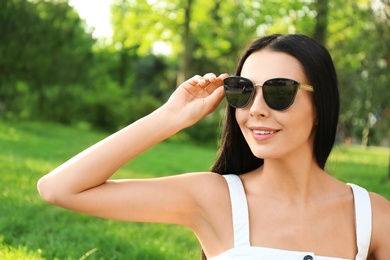 Photo of Beautiful young woman wearing stylish sunglasses in park