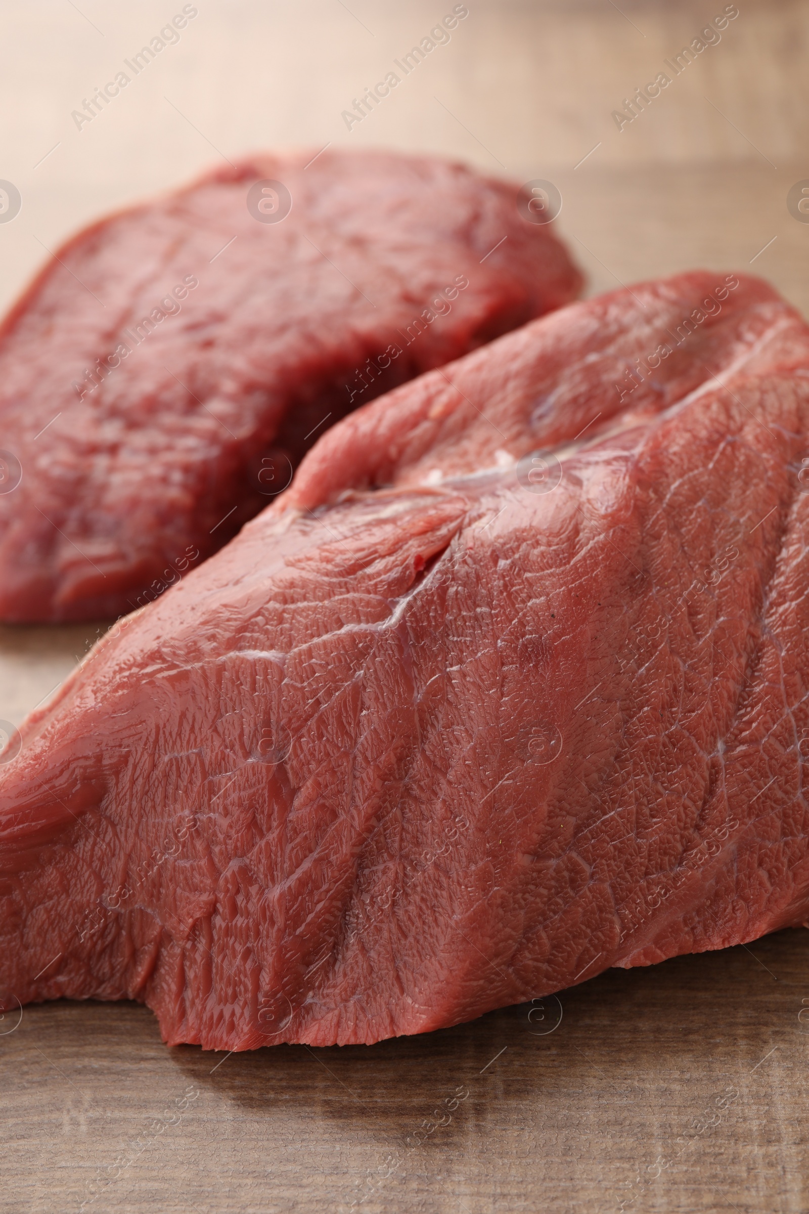 Photo of Pieces of raw beef meat on wooden table, closeup