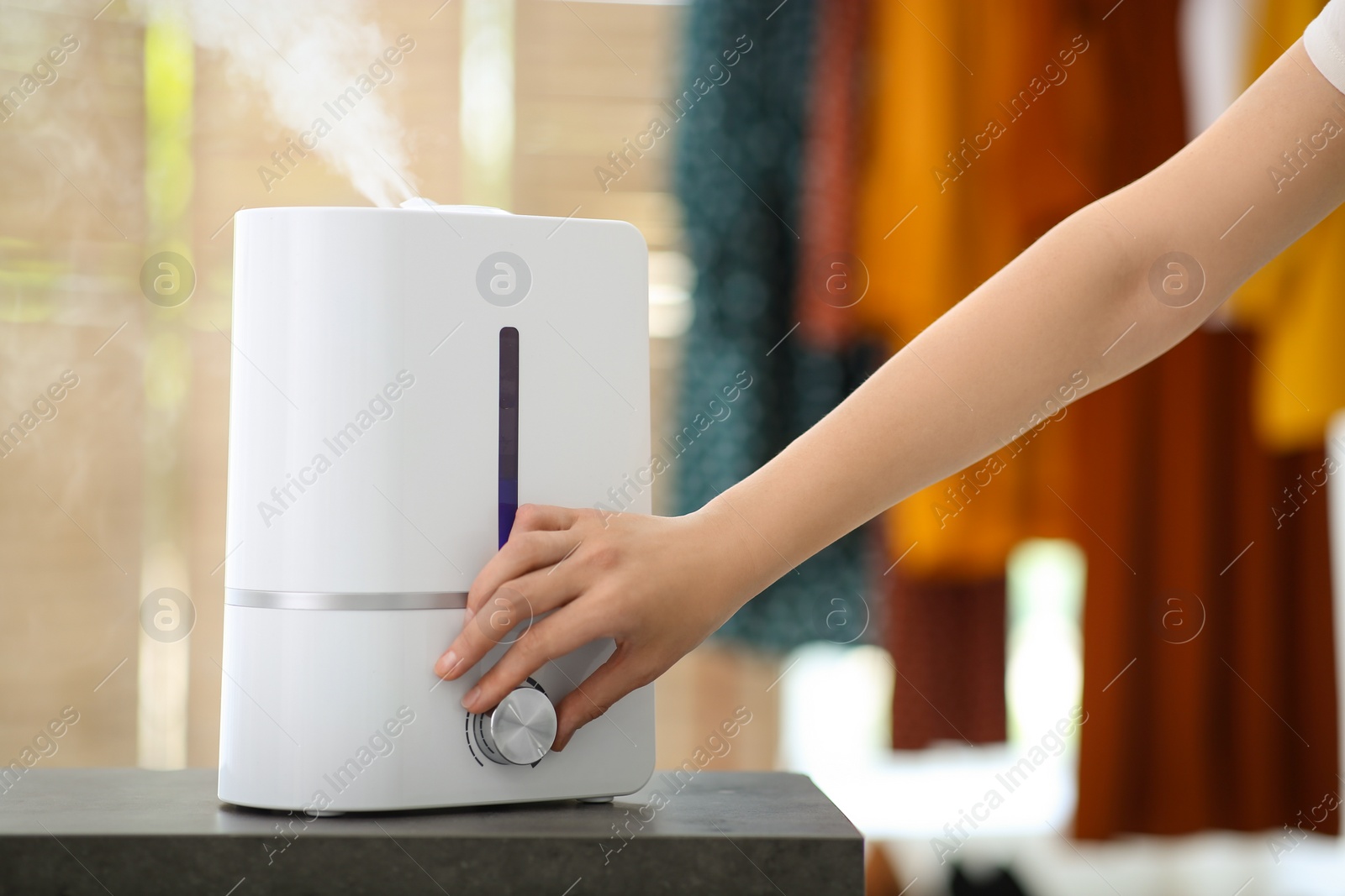 Photo of Woman turning on air humidifier indoors, closeup