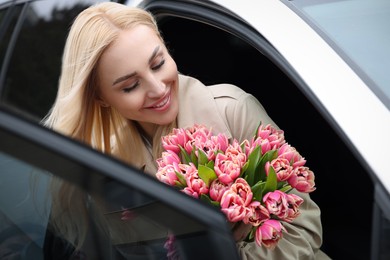 Photo of Happy young woman with beautiful bouquet in car