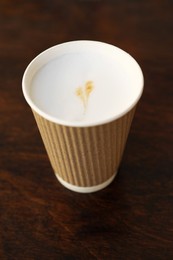 Photo of Delicious coffee in cardboard takeaway cup on wooden table, above view