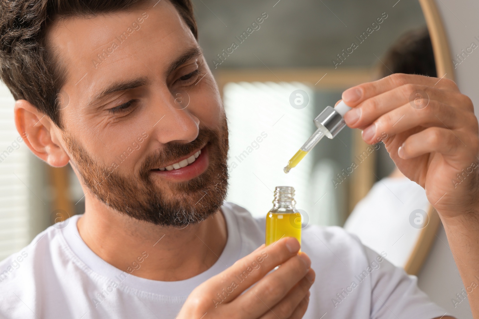 Photo of Smiling man with cosmetic serum indoors, closeup