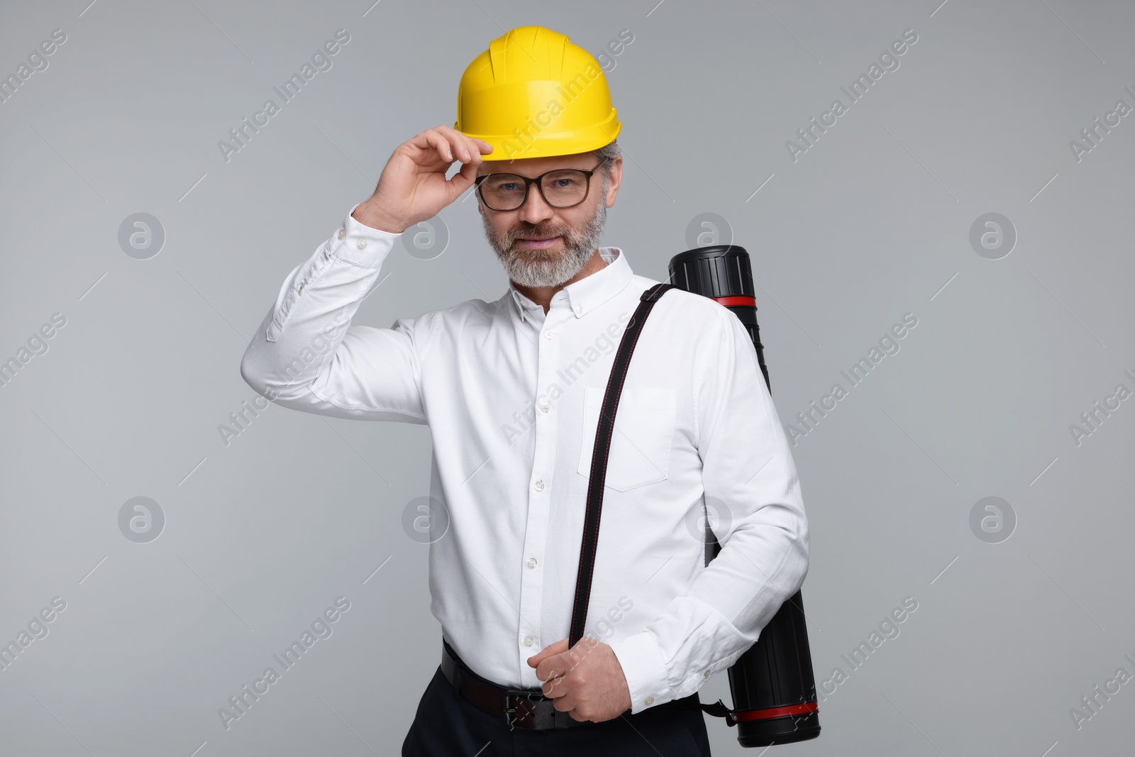 Photo of Architect in hard hat with drawing tube on grey background