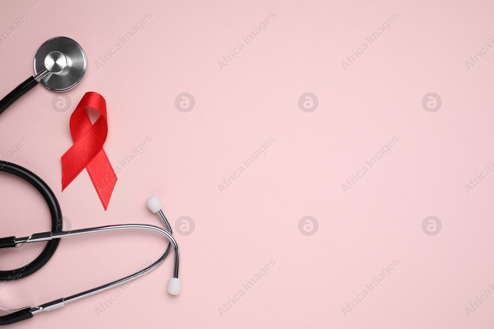 Photo of Red ribbon and stethoscope on pink background, flat lay with space for text. AIDS disease awareness