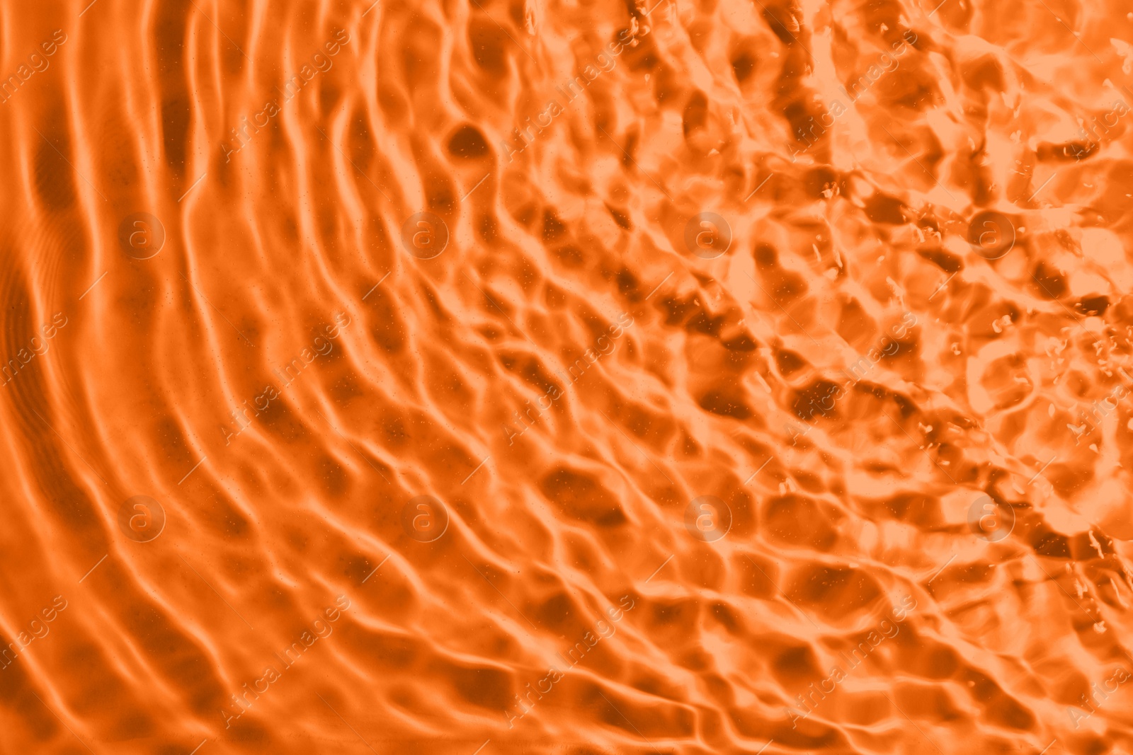 Image of Rippled surface of clear water on orange background