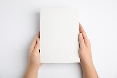 Photo of Woman holding book with blank cover on white background, top view