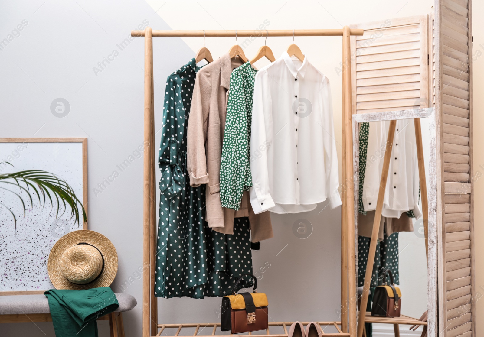 Photo of Wardrobe rack with women's clothes at color wall in room