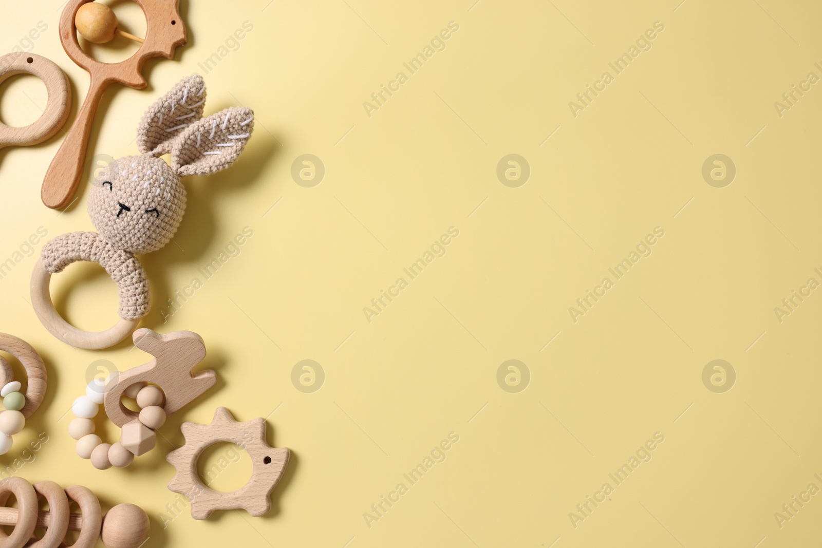 Photo of Baby accessories. Rattles and teethers on yellow background, flat lay. Space for text