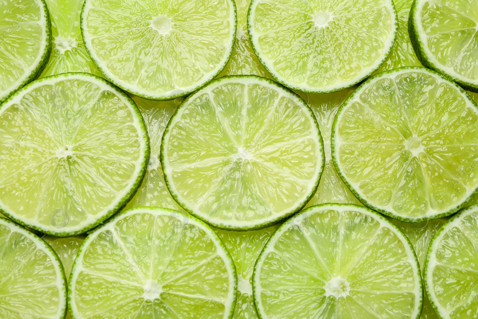 Photo of Many fresh juicy lime slices as background, top view