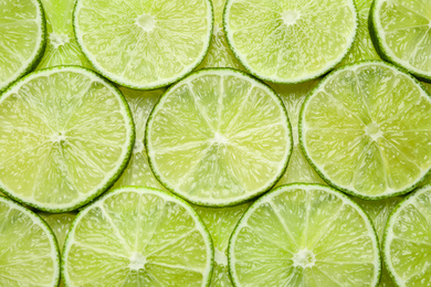 Many fresh juicy lime slices as background, top view