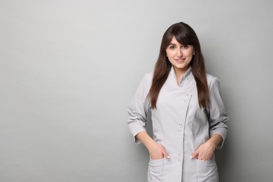 Photo of Cosmetologist in medical uniform on grey background, space for text