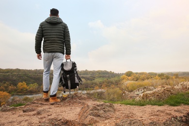 Photo of Traveler with backpack enjoying beautiful view near mountain river. Autumn vacation