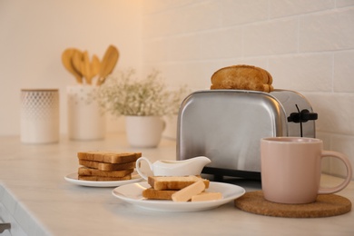 Modern toaster and tasty breakfast on counter in kitchen