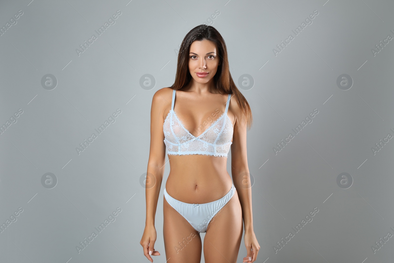 Photo of Beautiful woman in sexy panties and bra on light grey background