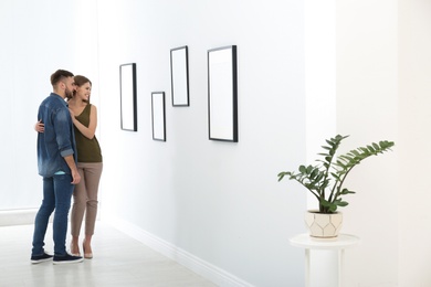 Photo of Young couple viewing exposition in modern art gallery