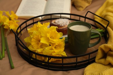 Photo of Bouquet of beautiful daffodils, bun and coffee on bed