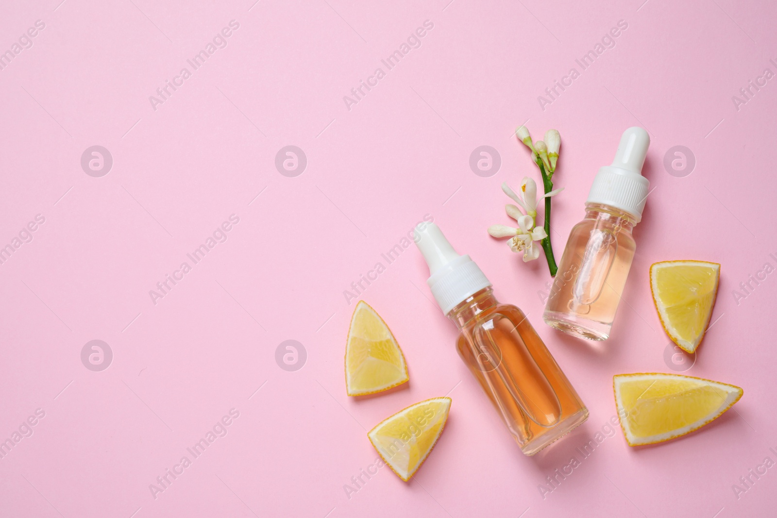 Photo of Flat lay composition with bottles of citrus essential oil on pink background. Space for text