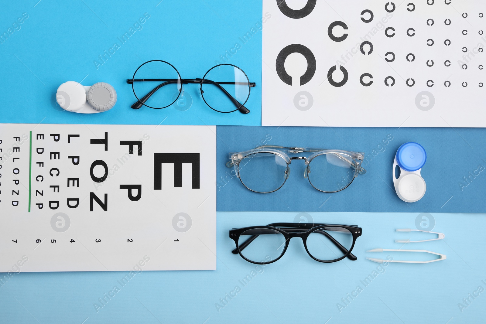 Photo of Vision test charts, glasses, lenses and tweezers on light blue background, flat lay