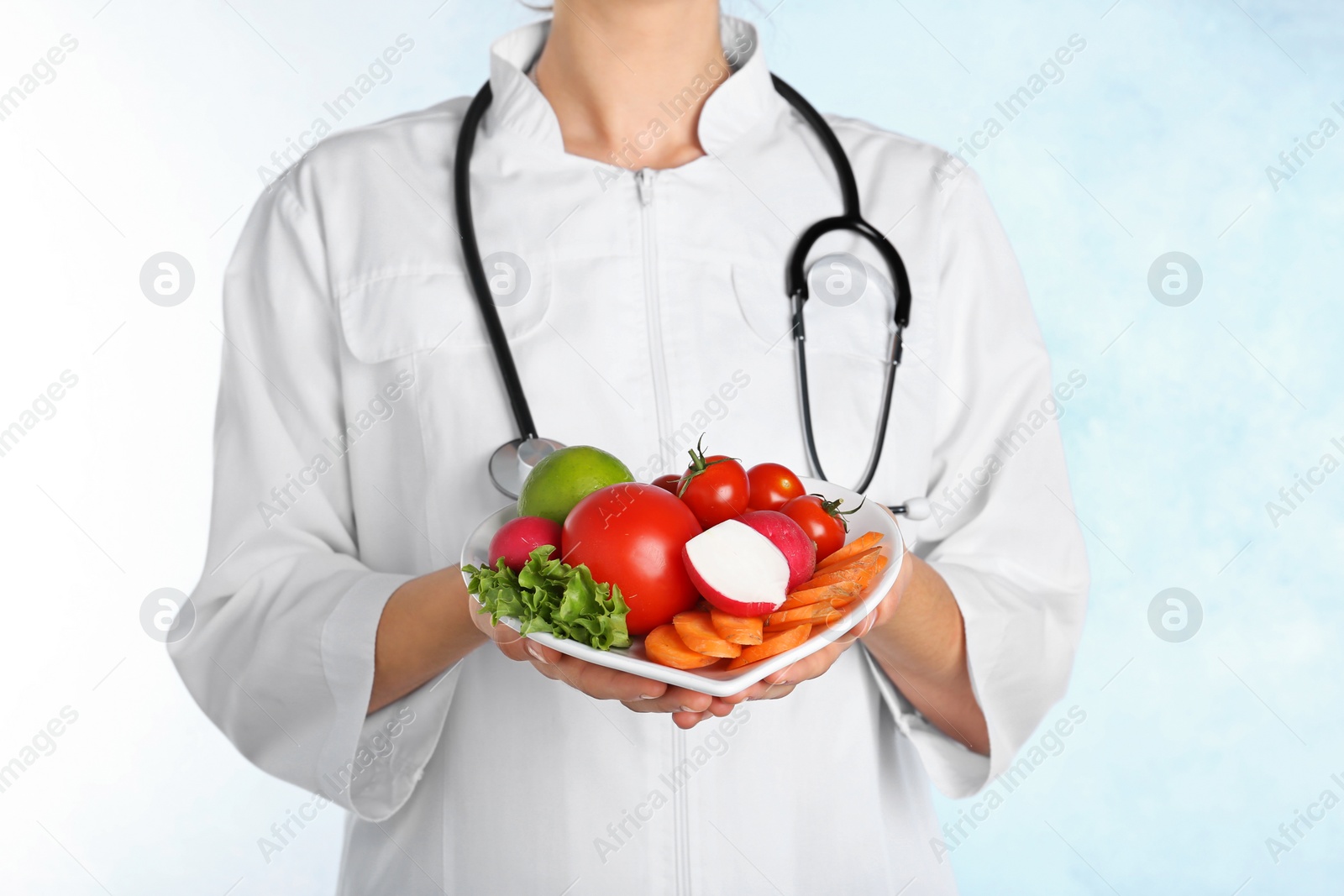 Photo of Female doctor with fresh products on light background. Cardiac diet