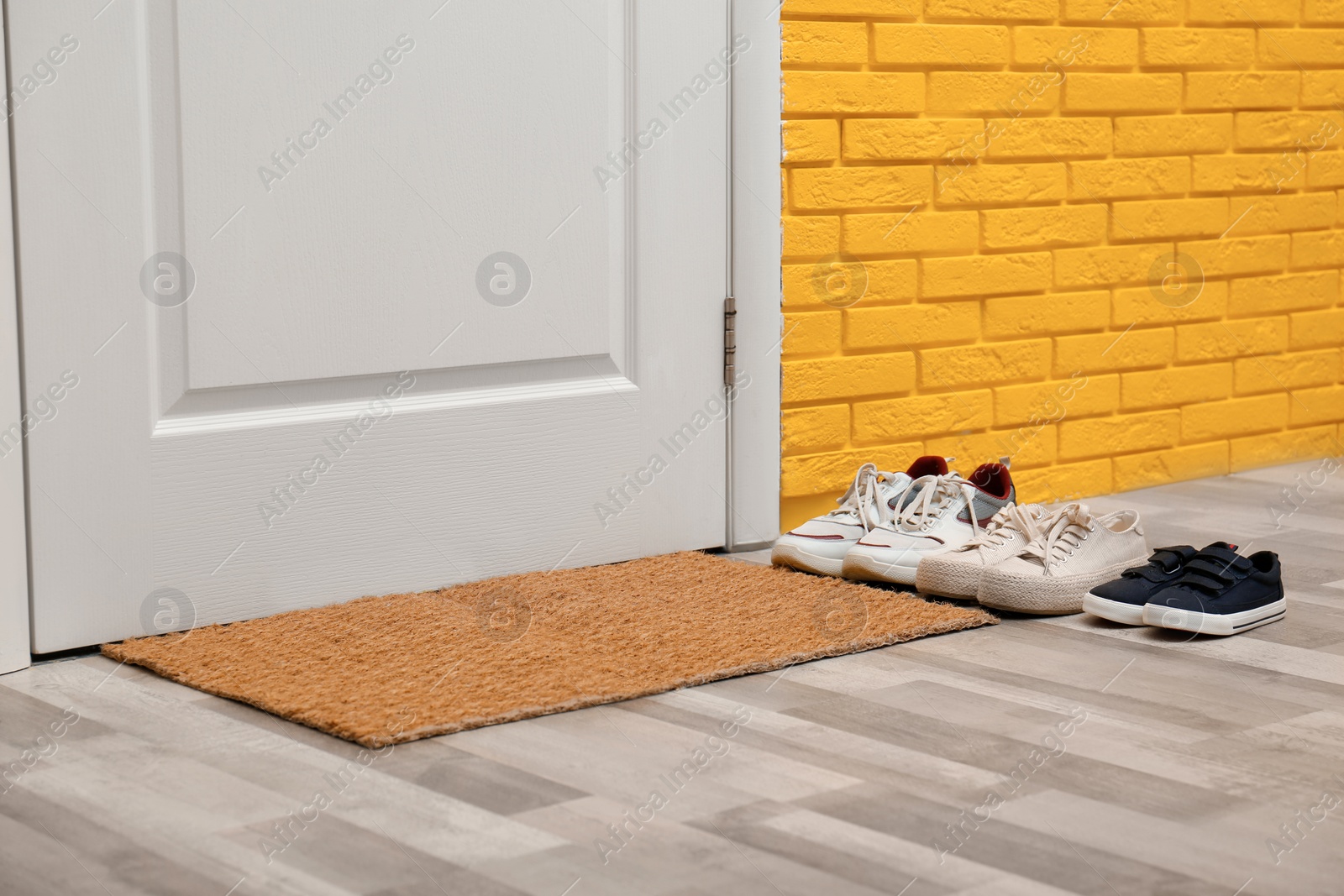 Photo of Stylish shoes and mat near door in hallway