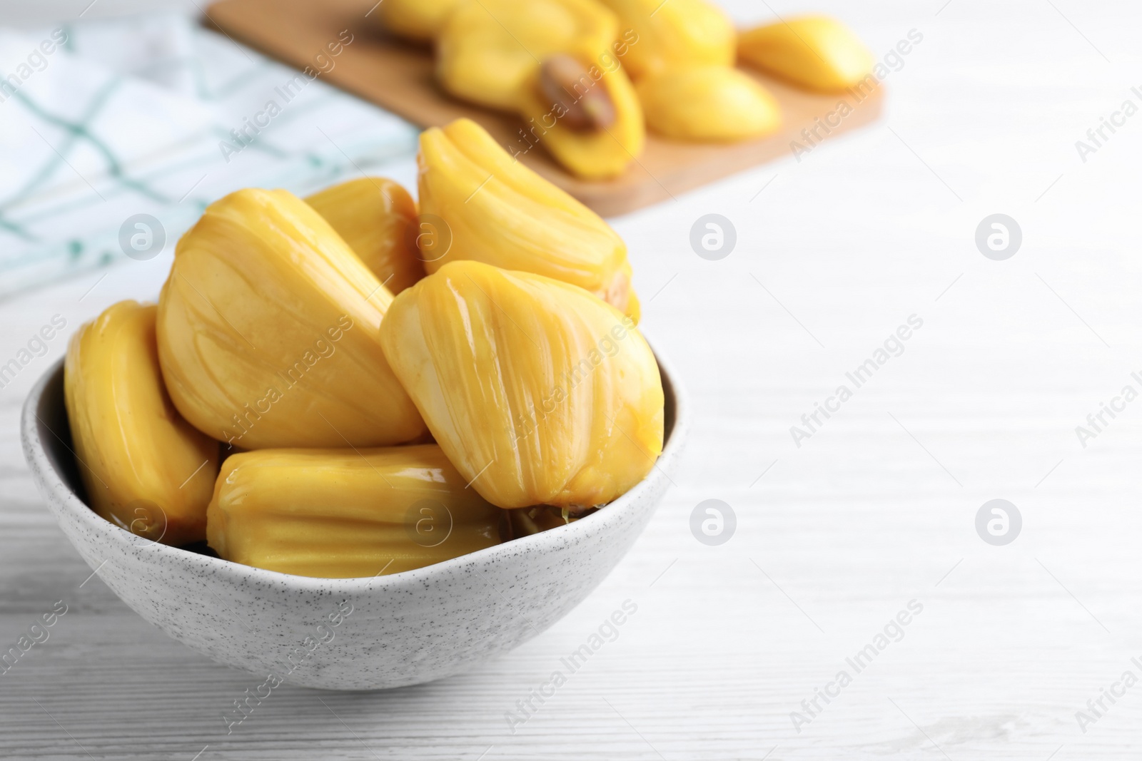 Photo of Delicious exotic jackfruit bulbs on white wooden table. Space for text