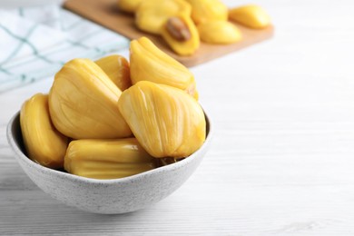 Photo of Delicious exotic jackfruit bulbs on white wooden table. Space for text