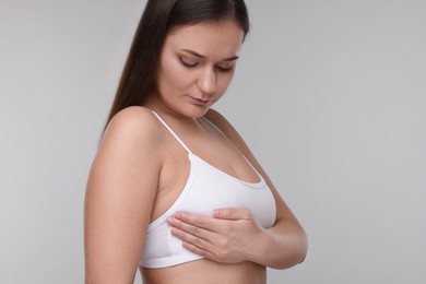 Mammology. Woman doing breast self-examination on light grey background