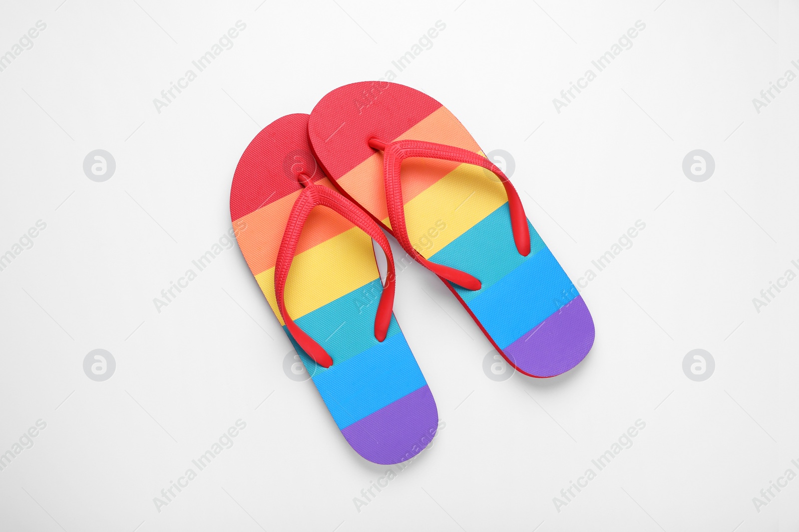 Photo of Stylish rainbow flip flops on white background, top view